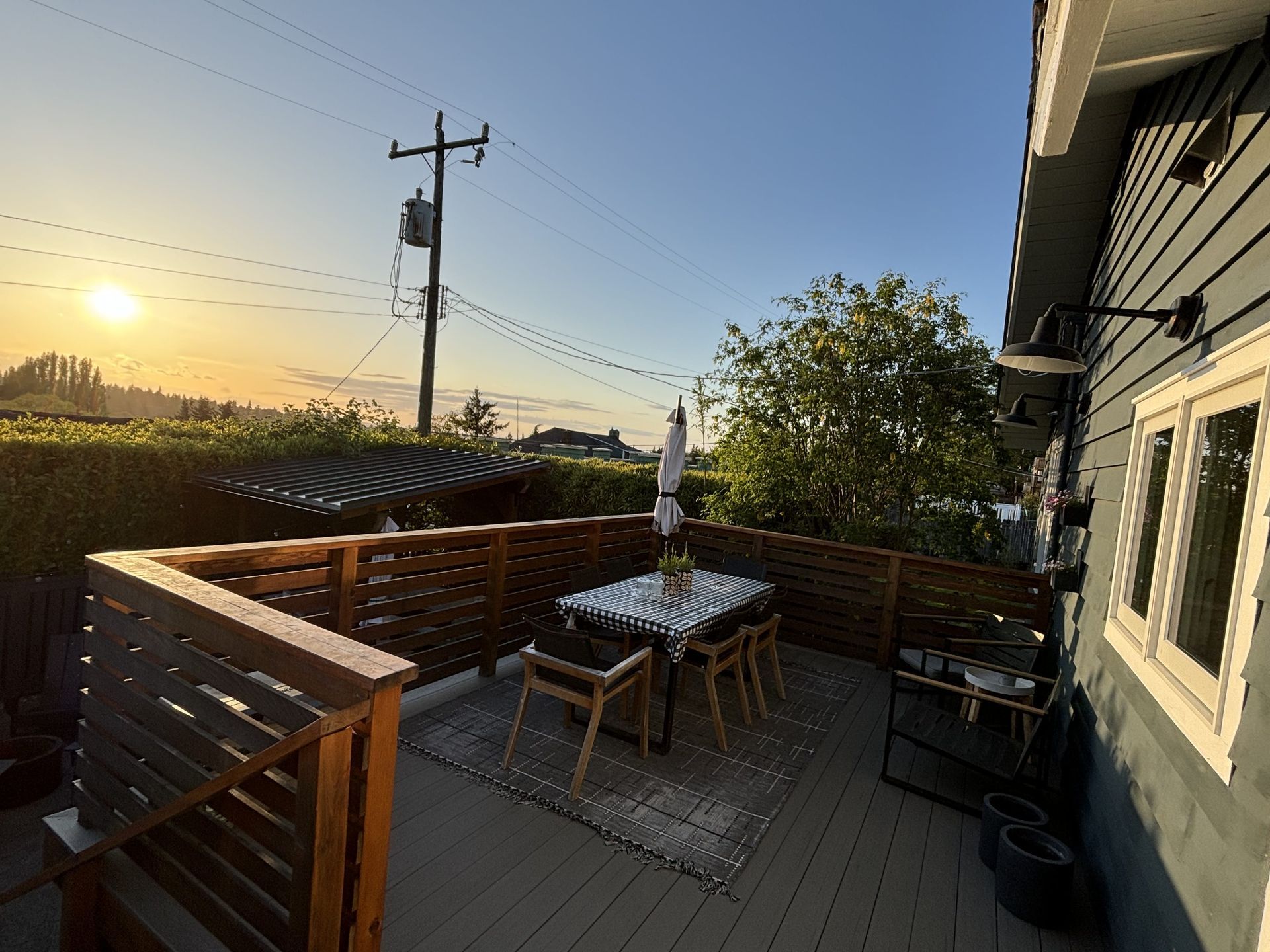 Backyard deck with table, chairs, umbrella, and sunset over fields