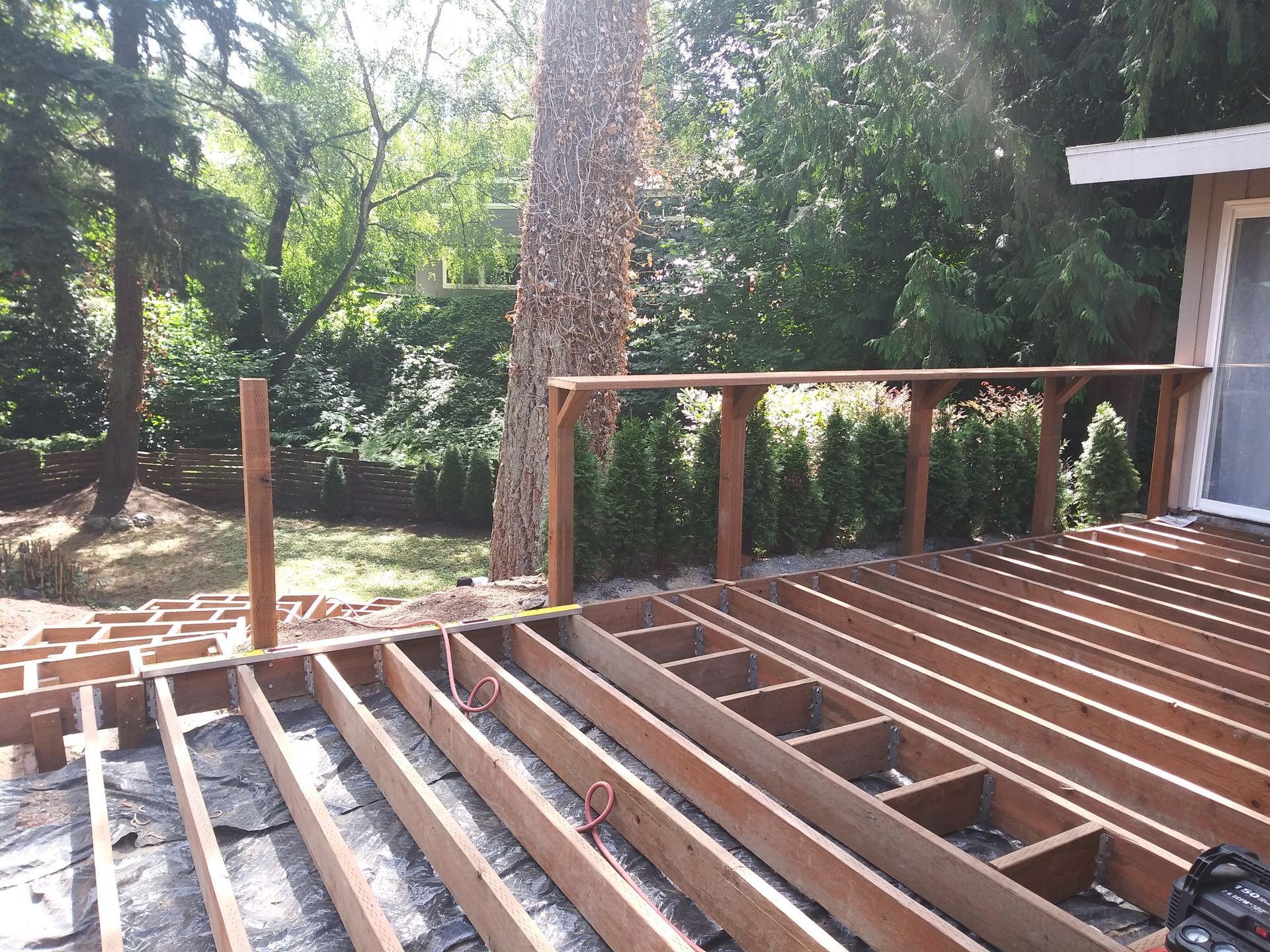 Partially built wooden deck with railings overlooking a wooded backyard