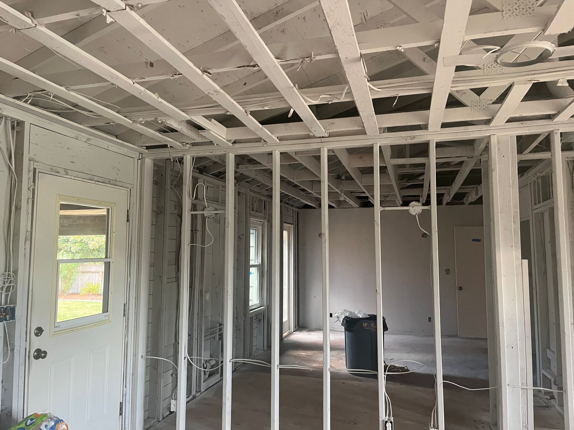 Unfinished room with exposed wooden studs, ceiling joists, and a window showing daylight.