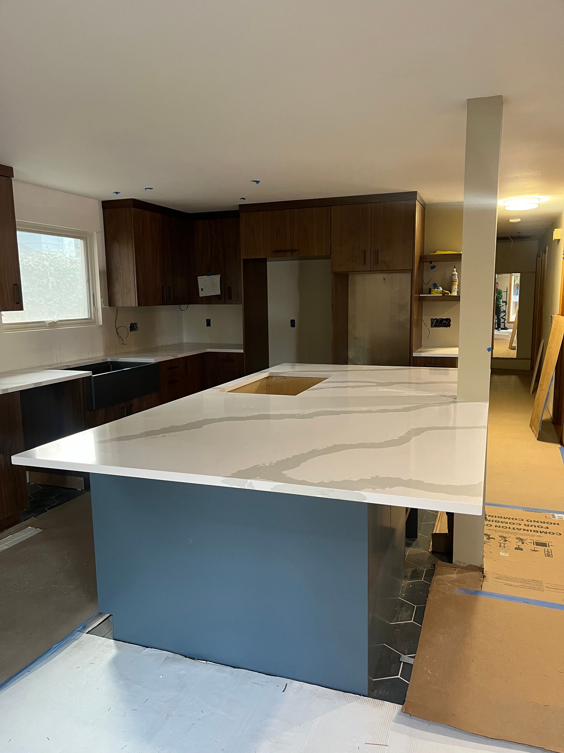 Modern kitchen with large white island, wood cabinets, and light tile floor.