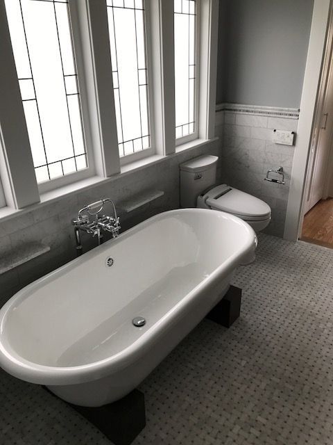 Accessible bathroom with a walk-in tub, toilet, and large windows and natural light