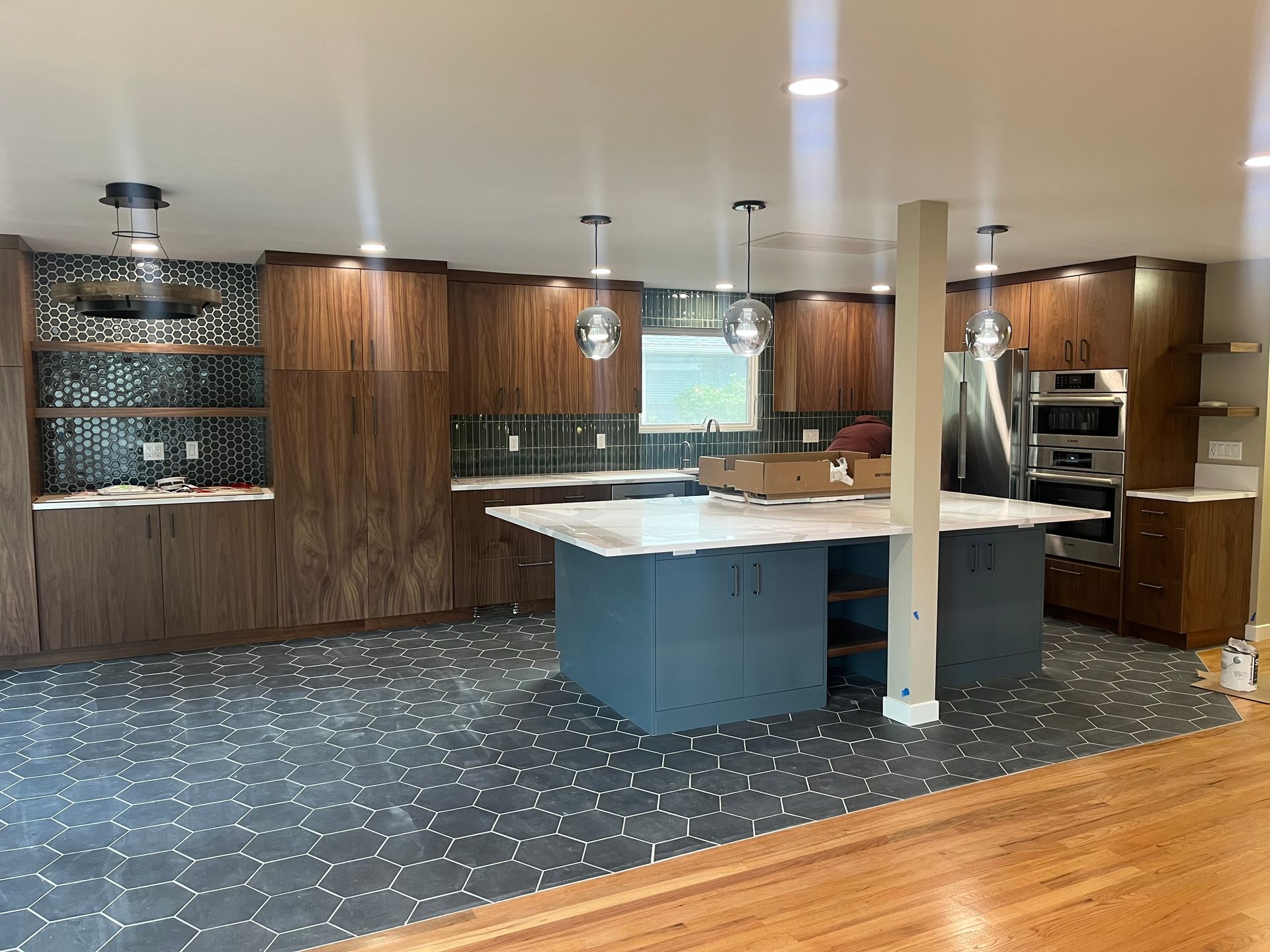 Modern kitchen with wood cabinets, gray island, tiled backsplash, and carpeted floor under pendant lights