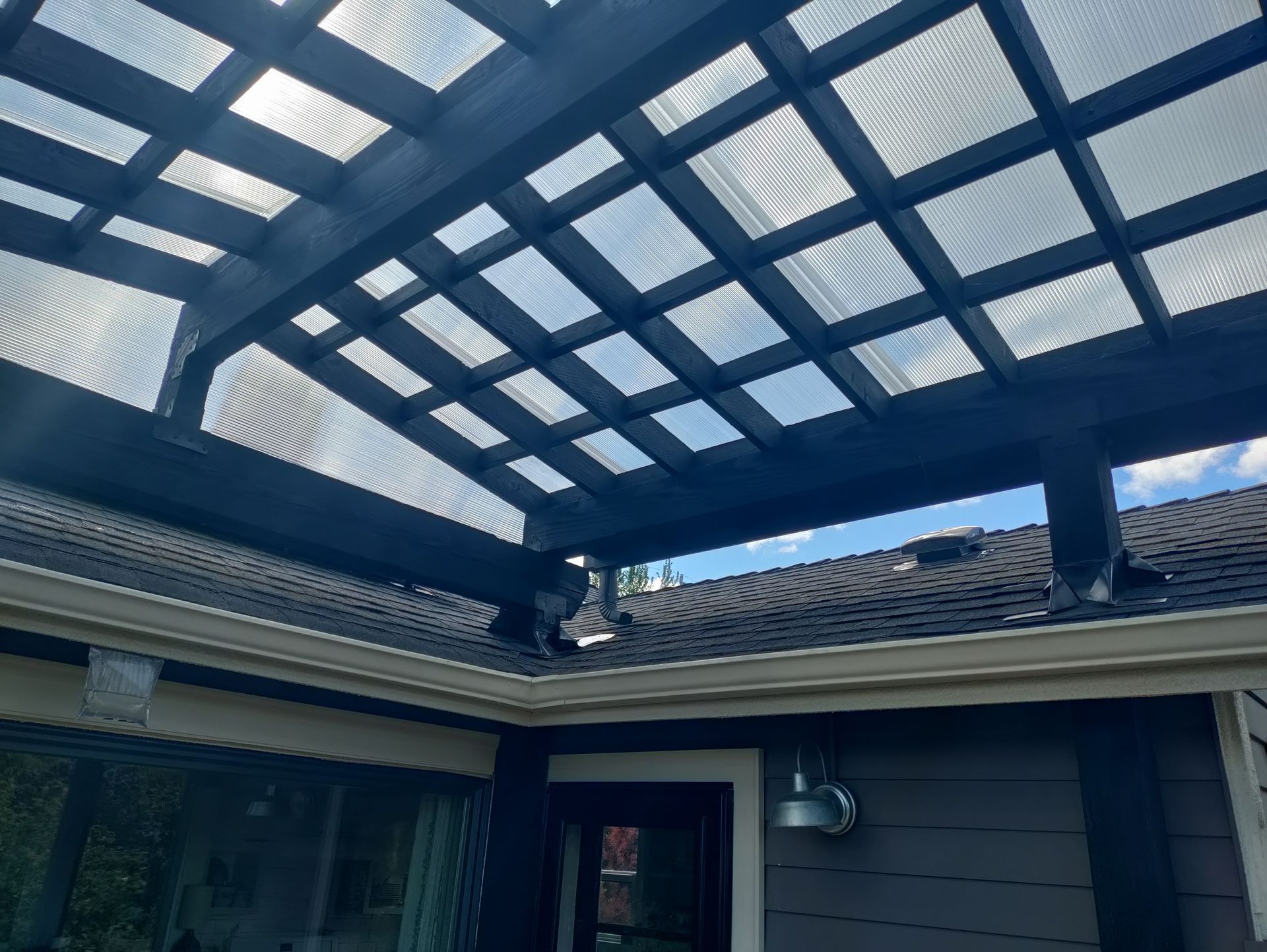 Covered patio with blue lattice roof and gray house exterior above a doorway