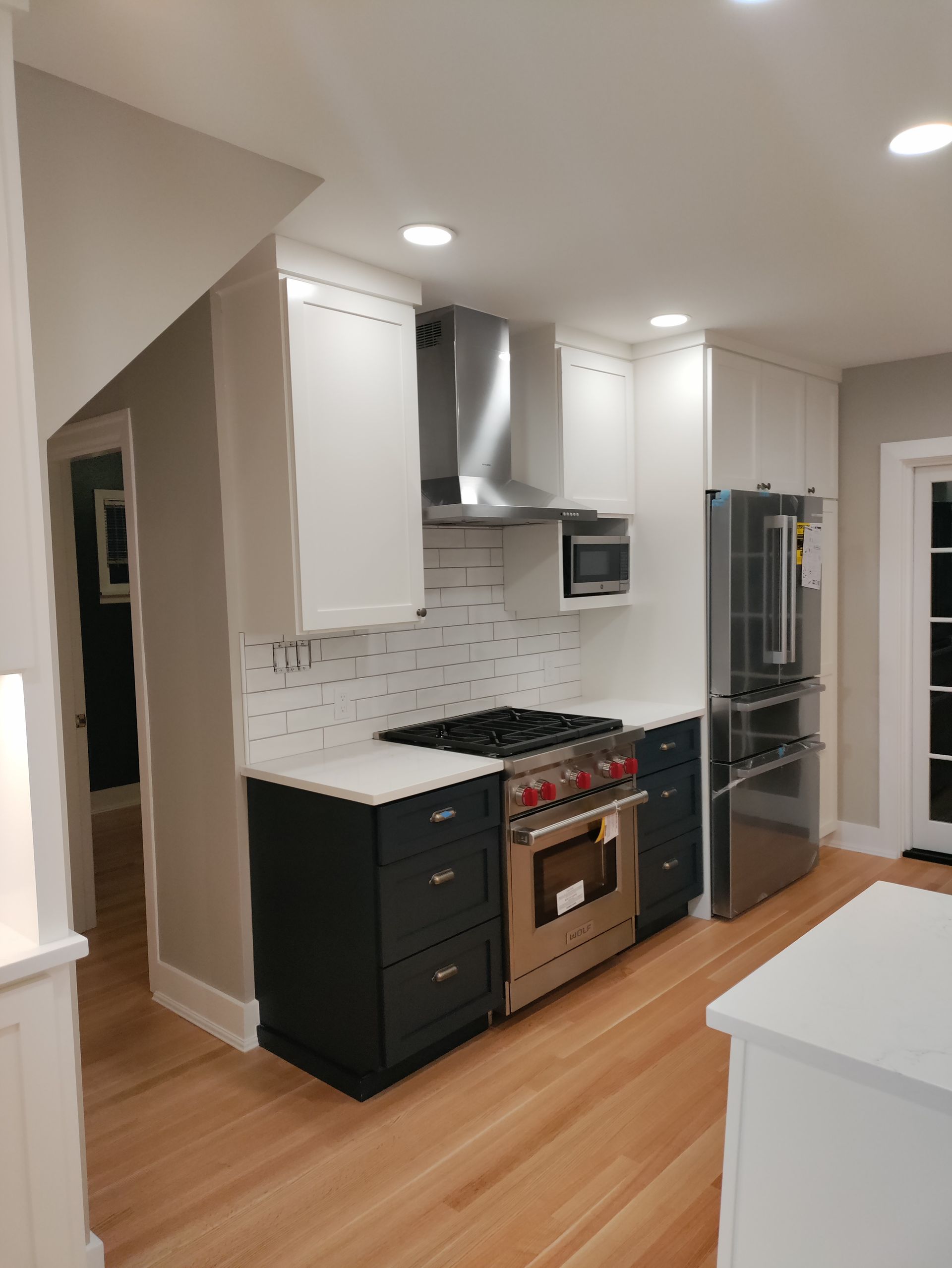Bright modern kitchen with white cabinets, stainless steel stove, and wood floors