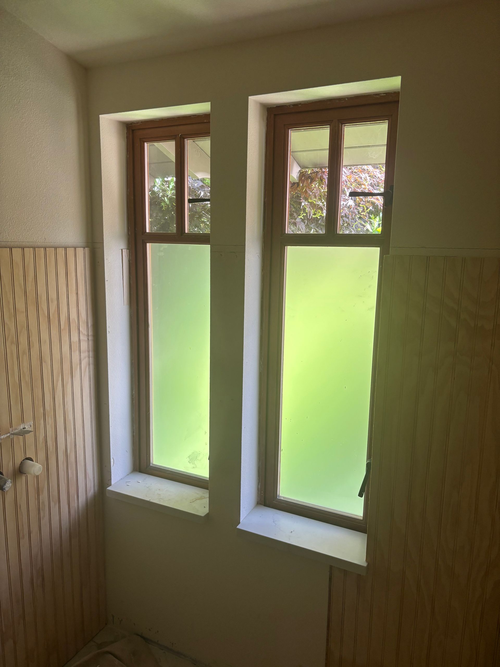 Small bathroom with two narrow frosted windows and beige patterned wall tiles.