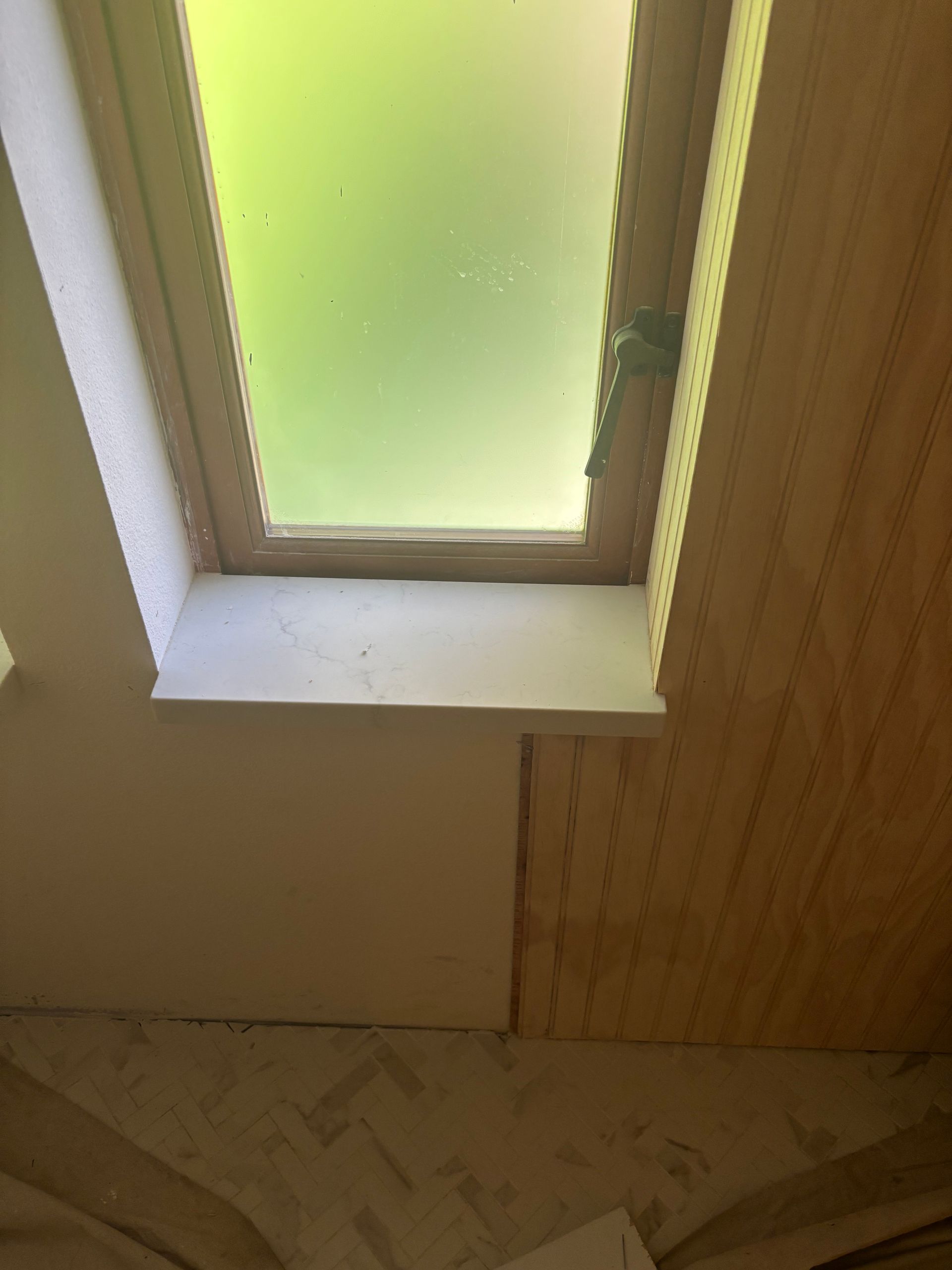 Small frosted skylight in a beige interior ceiling corner with wood paneling nearby