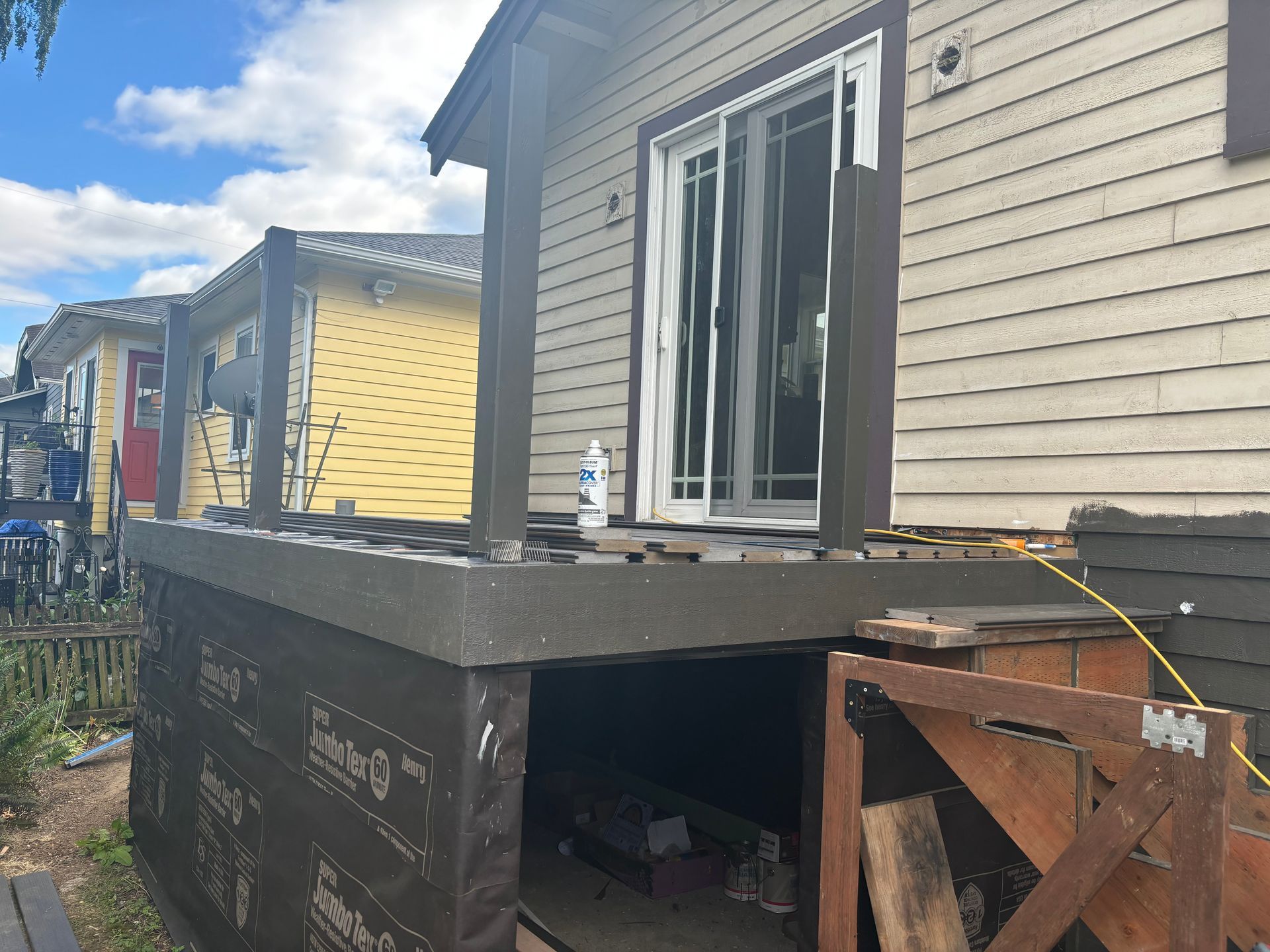 House exterior with a raised back porch and open sliding door, showing an unfinished under-deck area