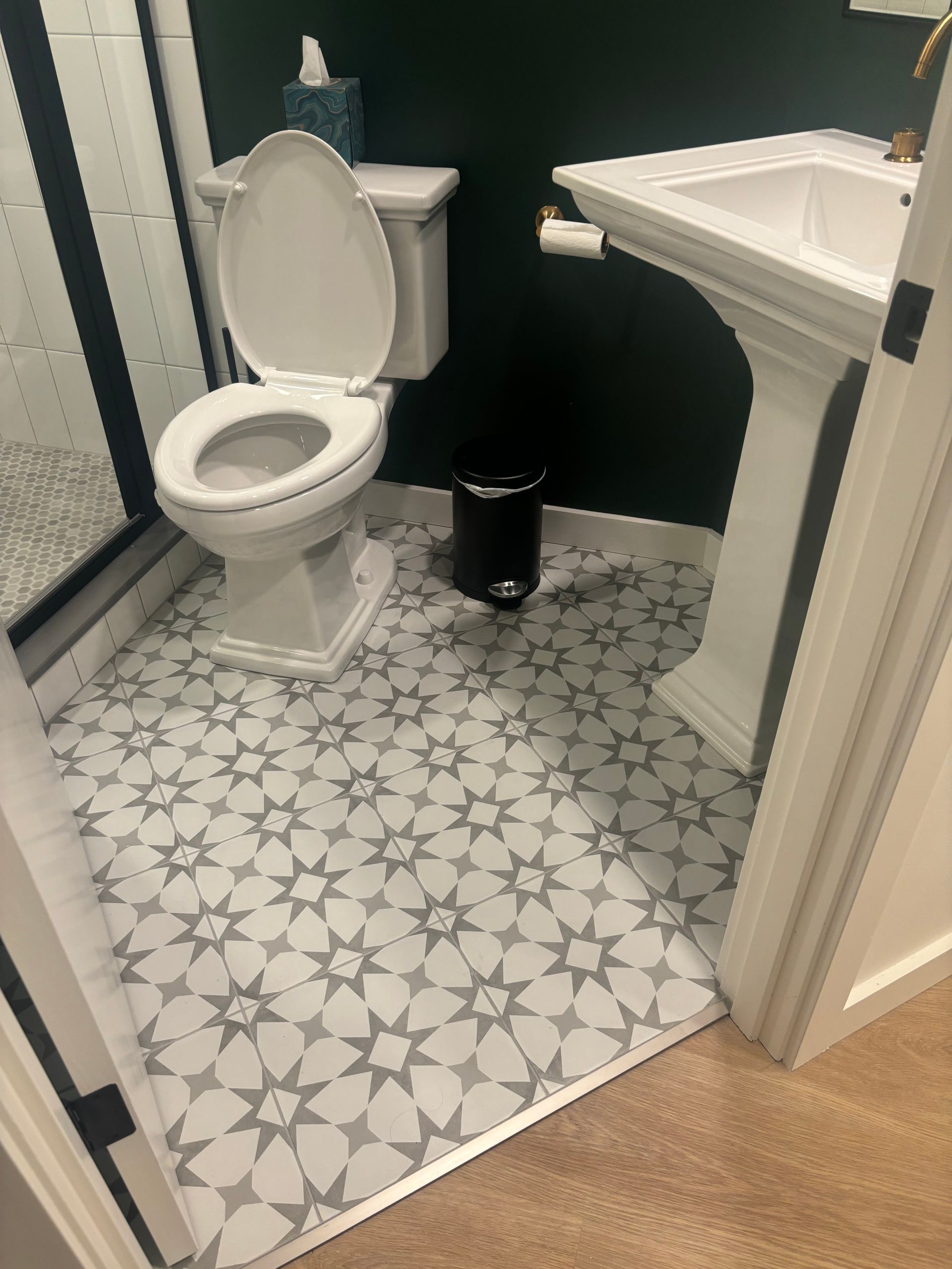 Small bathroom with toilet, pedestal sink, dark walls, and gray patterned tile floor.