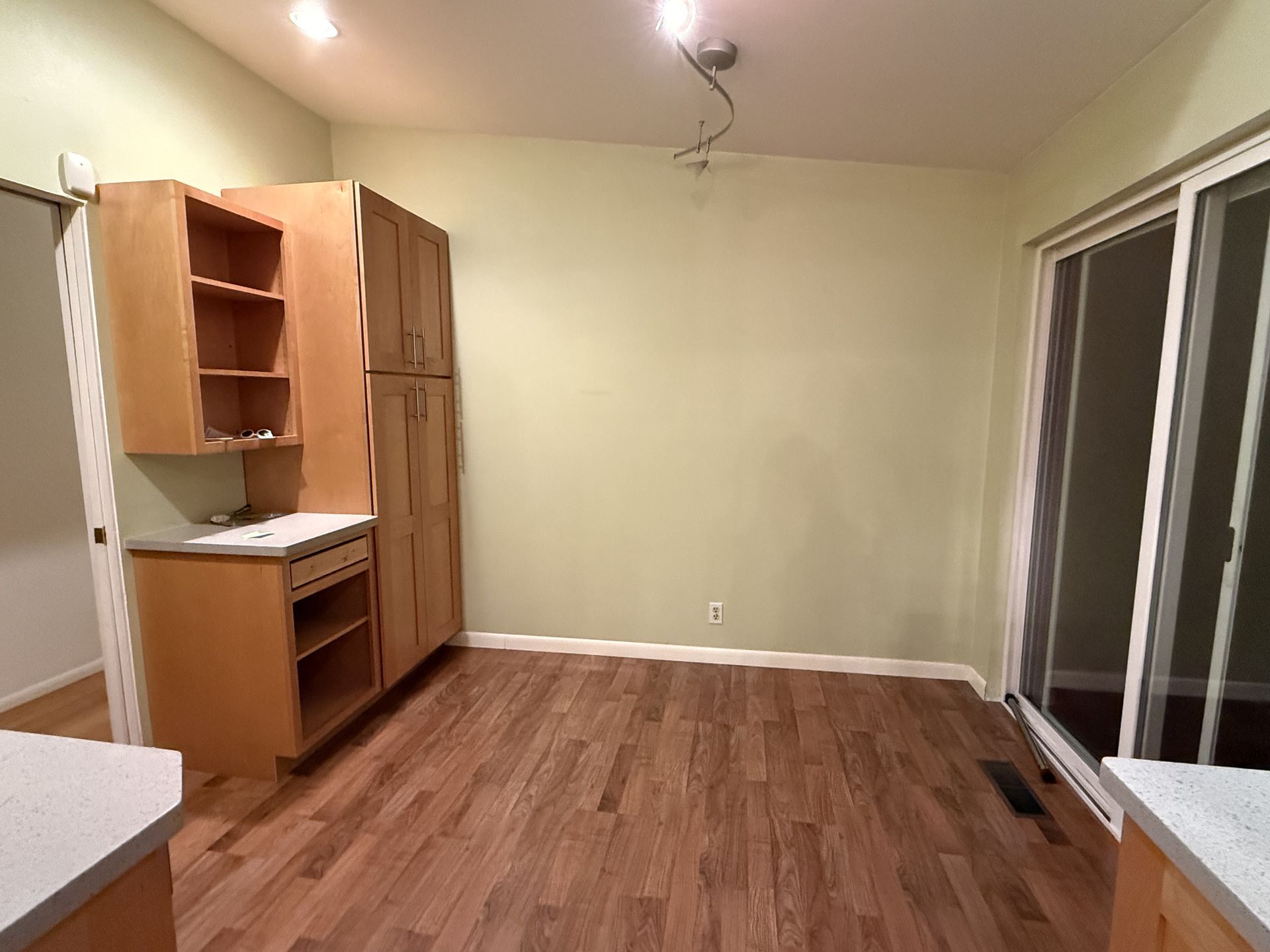 Empty room with wood floor, built-in cabinets, and sliding glass doors on the right.