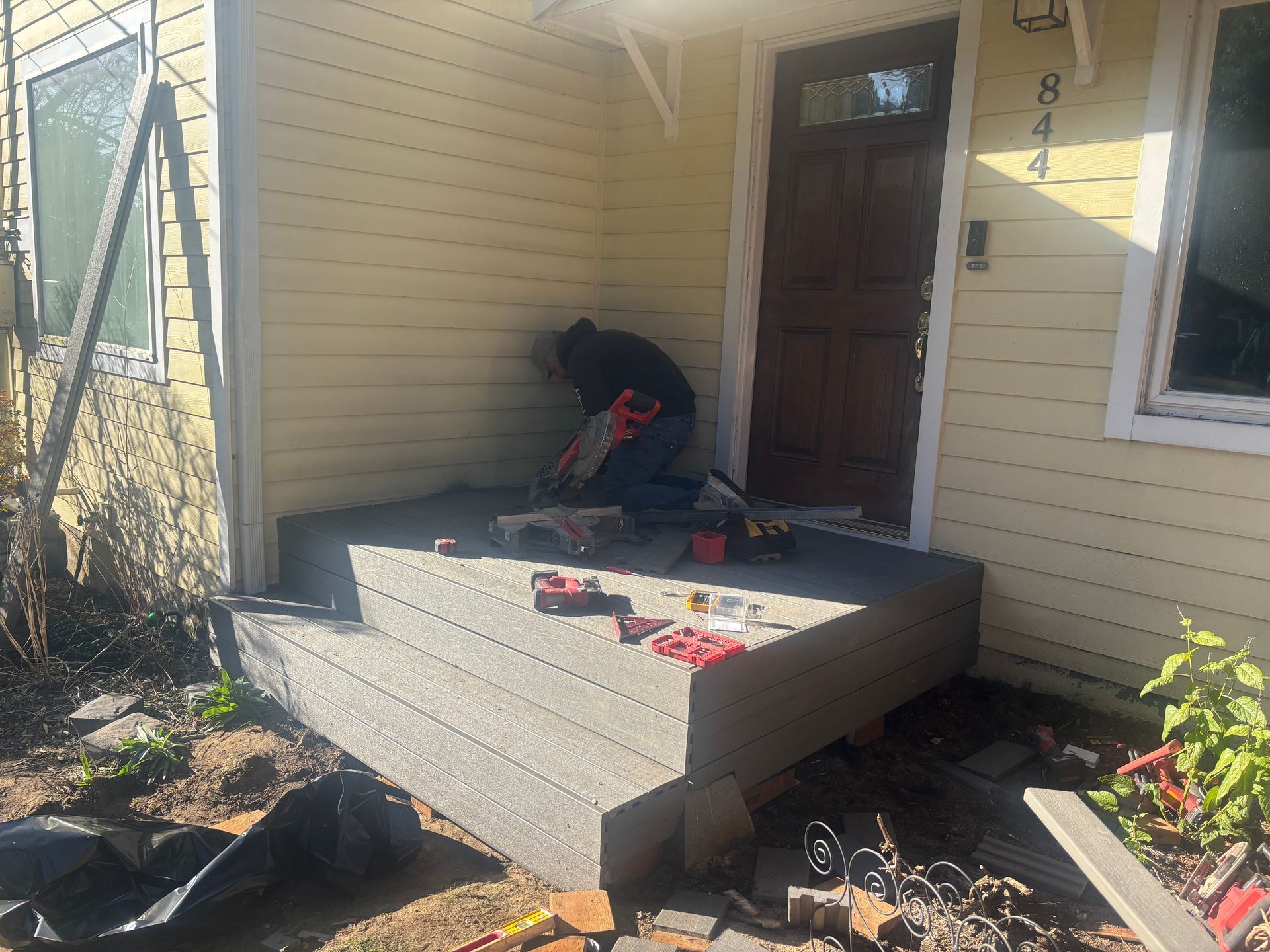Person using a power drill on a small front porch deck under construction