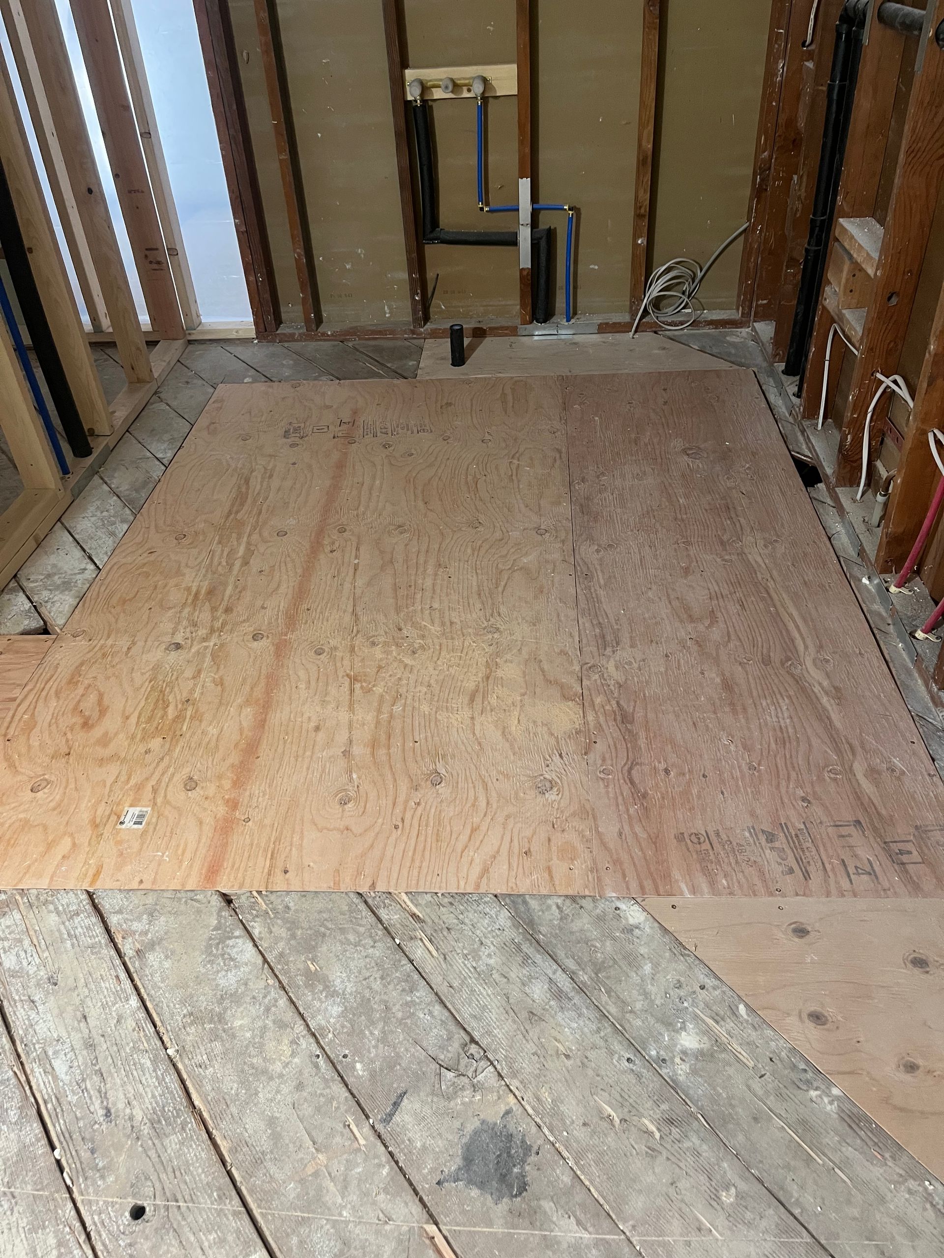 Unfinished room with exposed wall studs and plywood subfloor under construction