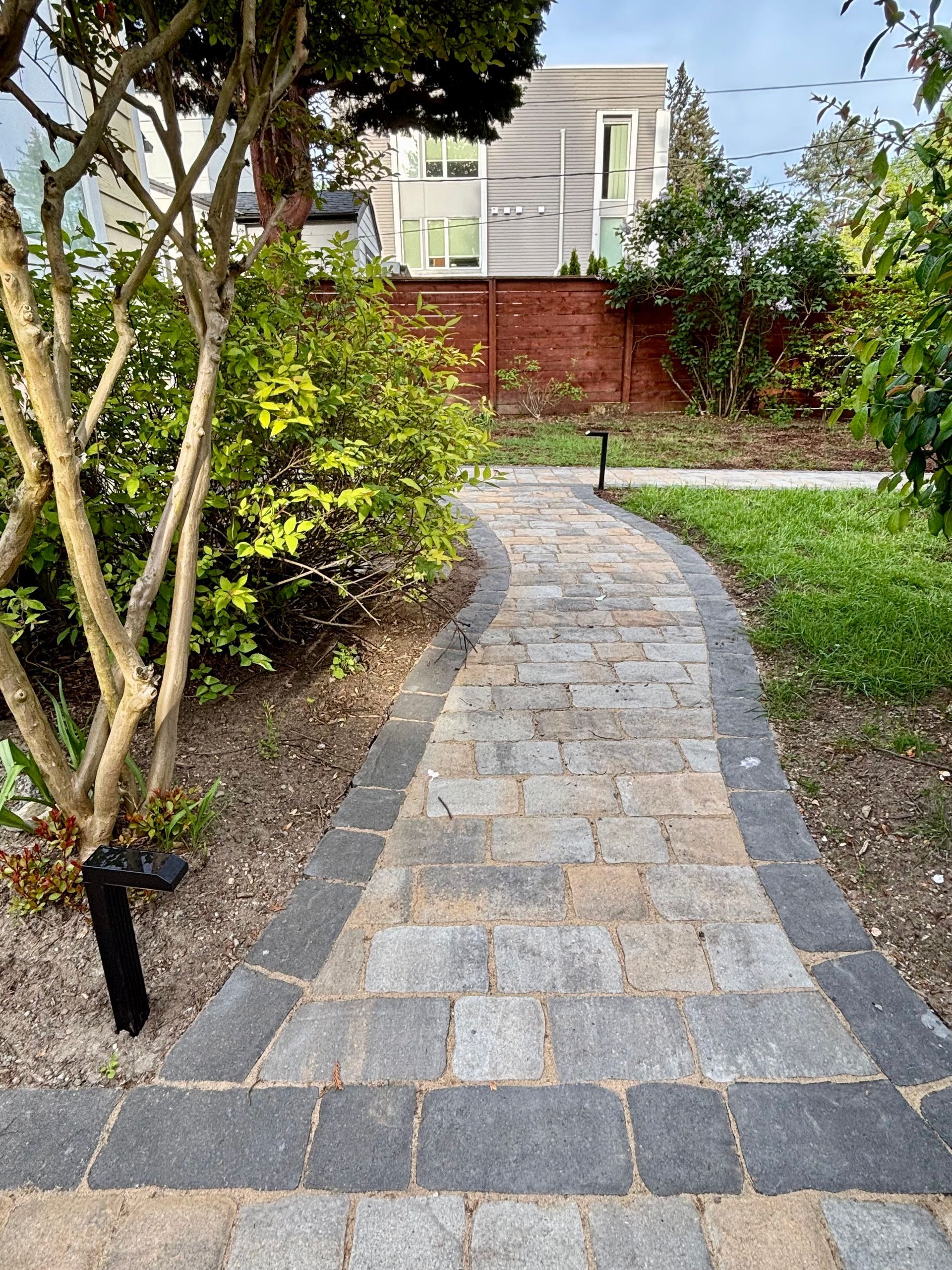 Stone walkway winding through a landscaped garden toward a house