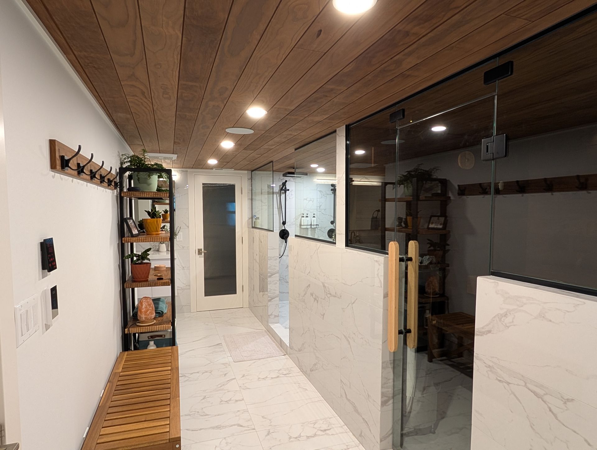 Modern hallway with wood ceiling, white marble walls, glass panels, and built-in shelves