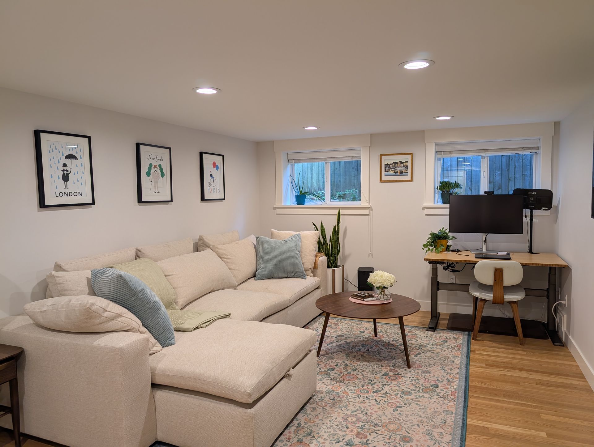 Cozy living room with beige sectional sofa, coffee table, patterned rug, and a desk by the window