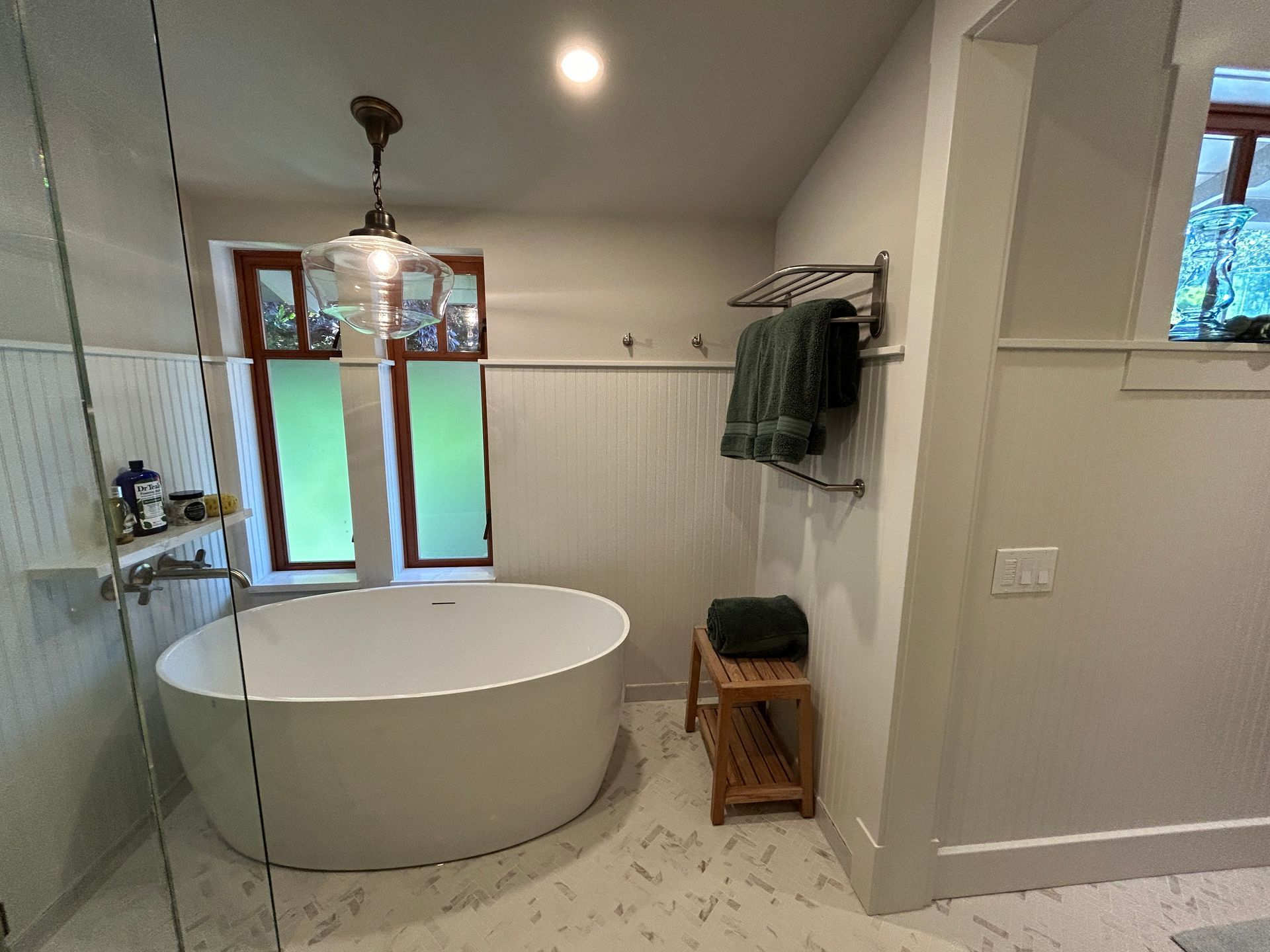 Modern bathroom with a freestanding tub, glass shower, and wall-mounted towel rack near a window.