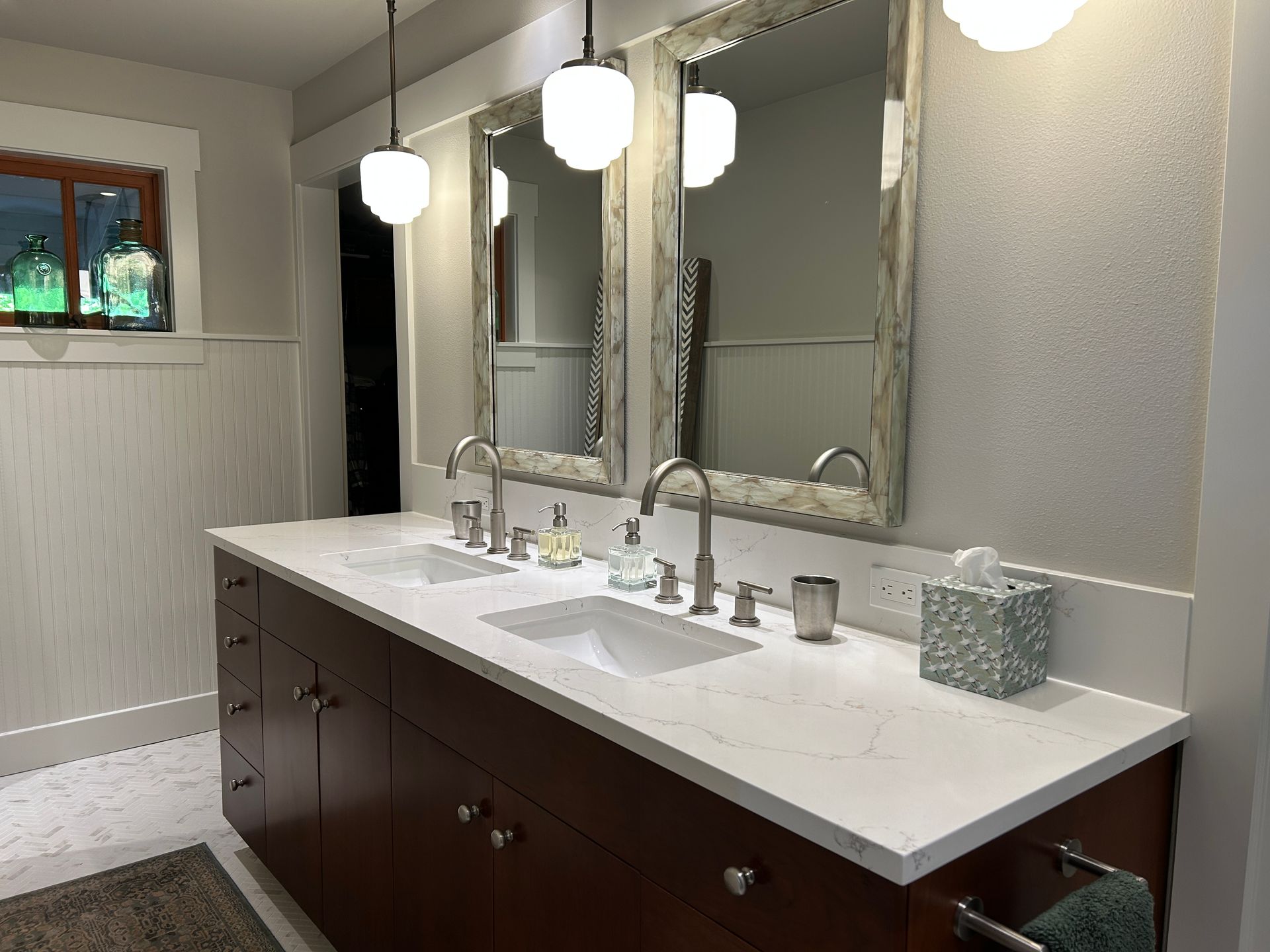 Modern bathroom vanity with double sinks, large mirrors, pendant lights, and dark wood cabinets