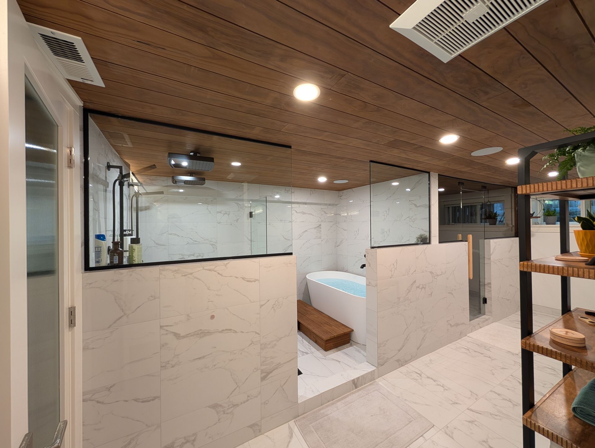 Modern bathroom with marble walls, wood ceiling, glass shower, and built-in wooden bench