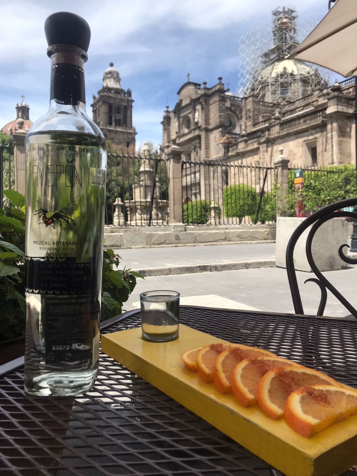 Una botella de tequila se encuentra en una mesa junto a un plato con rodajas de naranja.