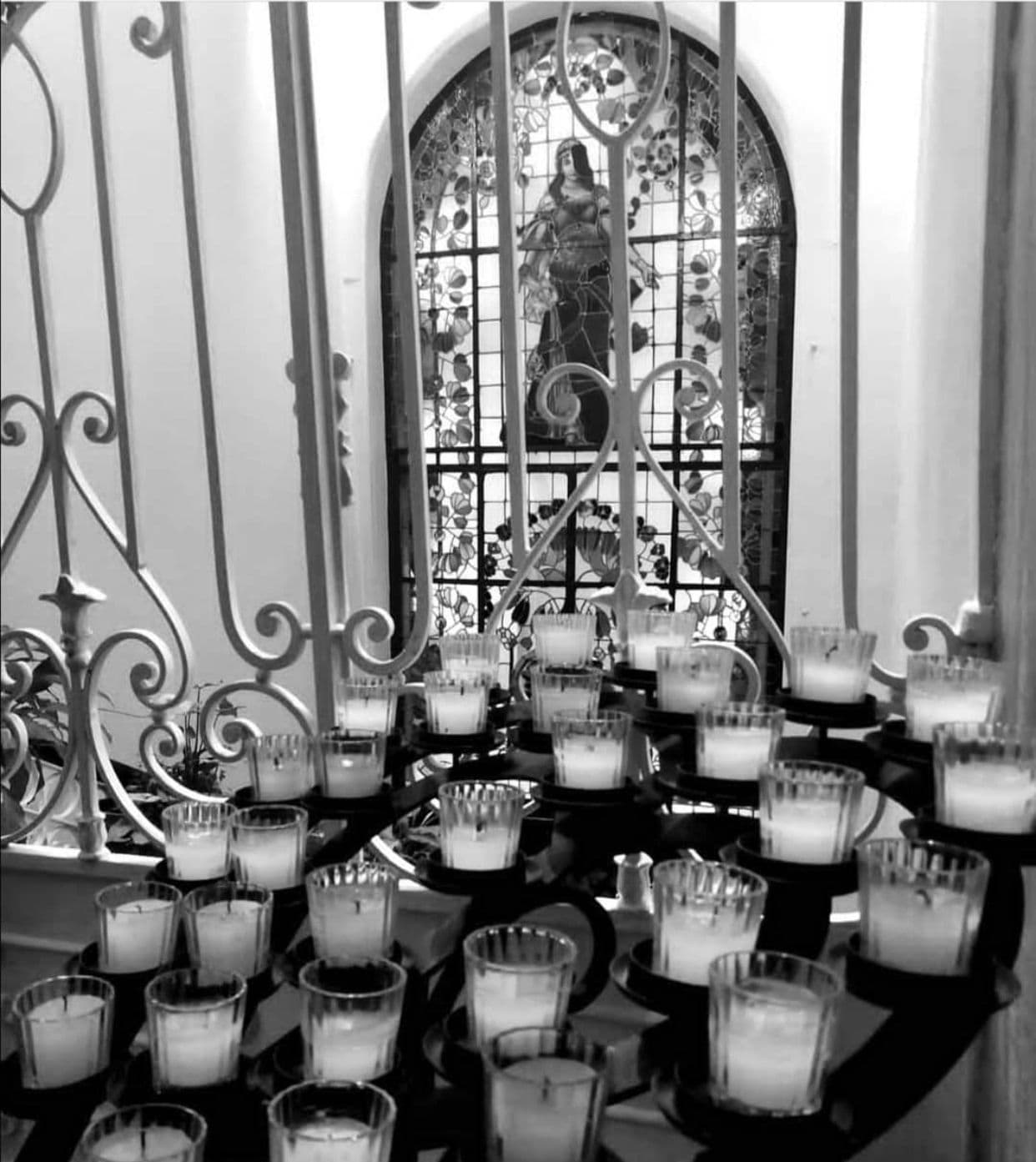 Una fotografía en blanco y negro de velas frente a una vidriera