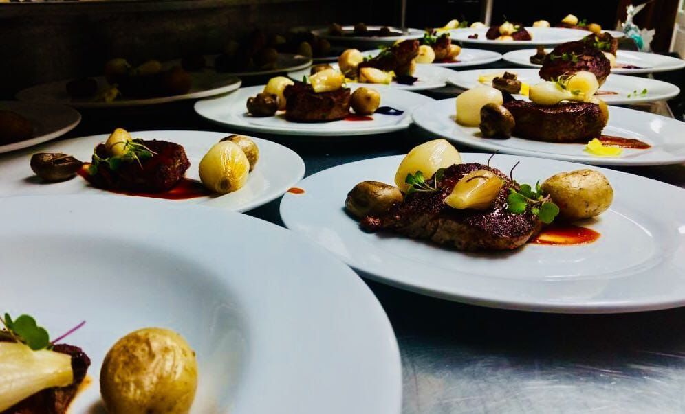 Una fila de platos blancos llenos de comida sobre una mesa