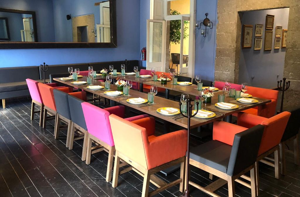 Un comedor con mesas y sillas y un gran espejo