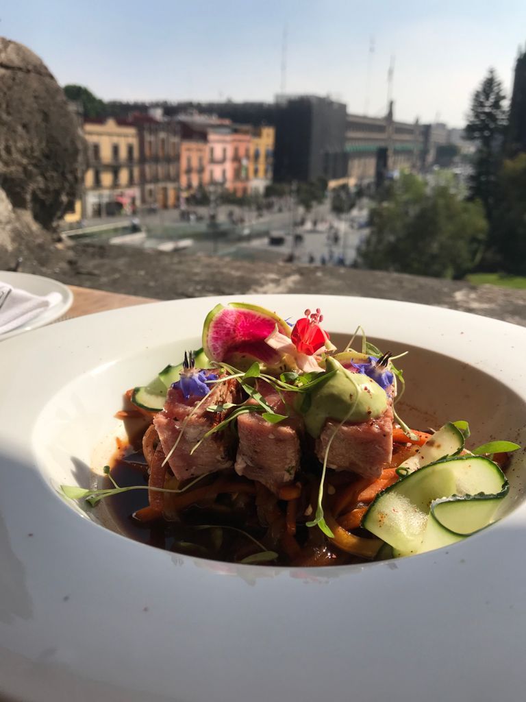 Un primer plano de un plato de comida con una ciudad al fondo.