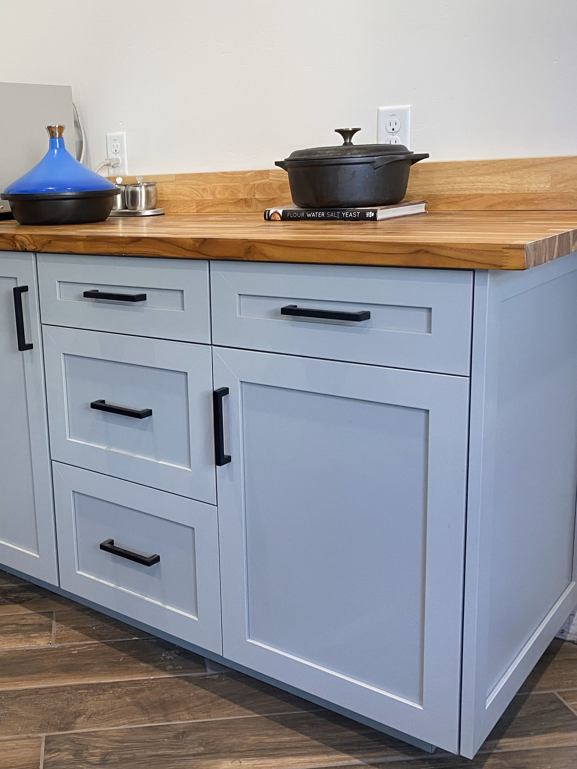 A pot is sitting on top of a wooden counter in a kitchen.