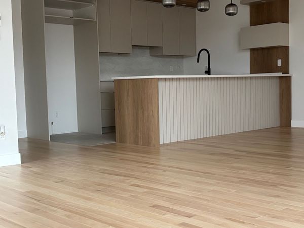 Cuisine avec parquet clair, placards blancs et en bois, et robinet noir.