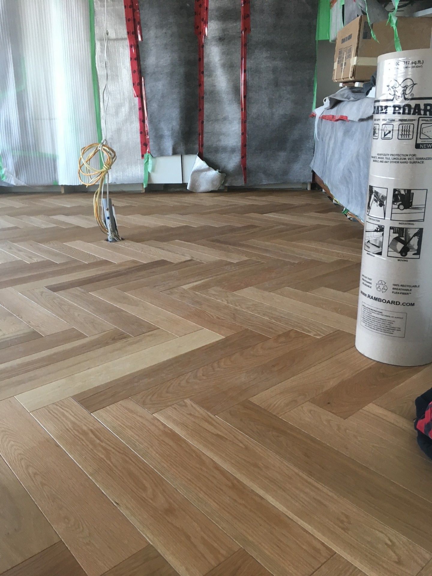 Plancher en bois franc à chevrons dans une pièce en construction.