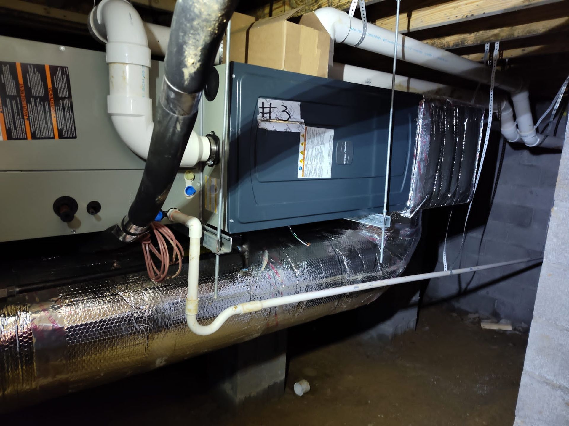 Ductwork and pipes in a flooded basement utility area, with standing water on the floor.