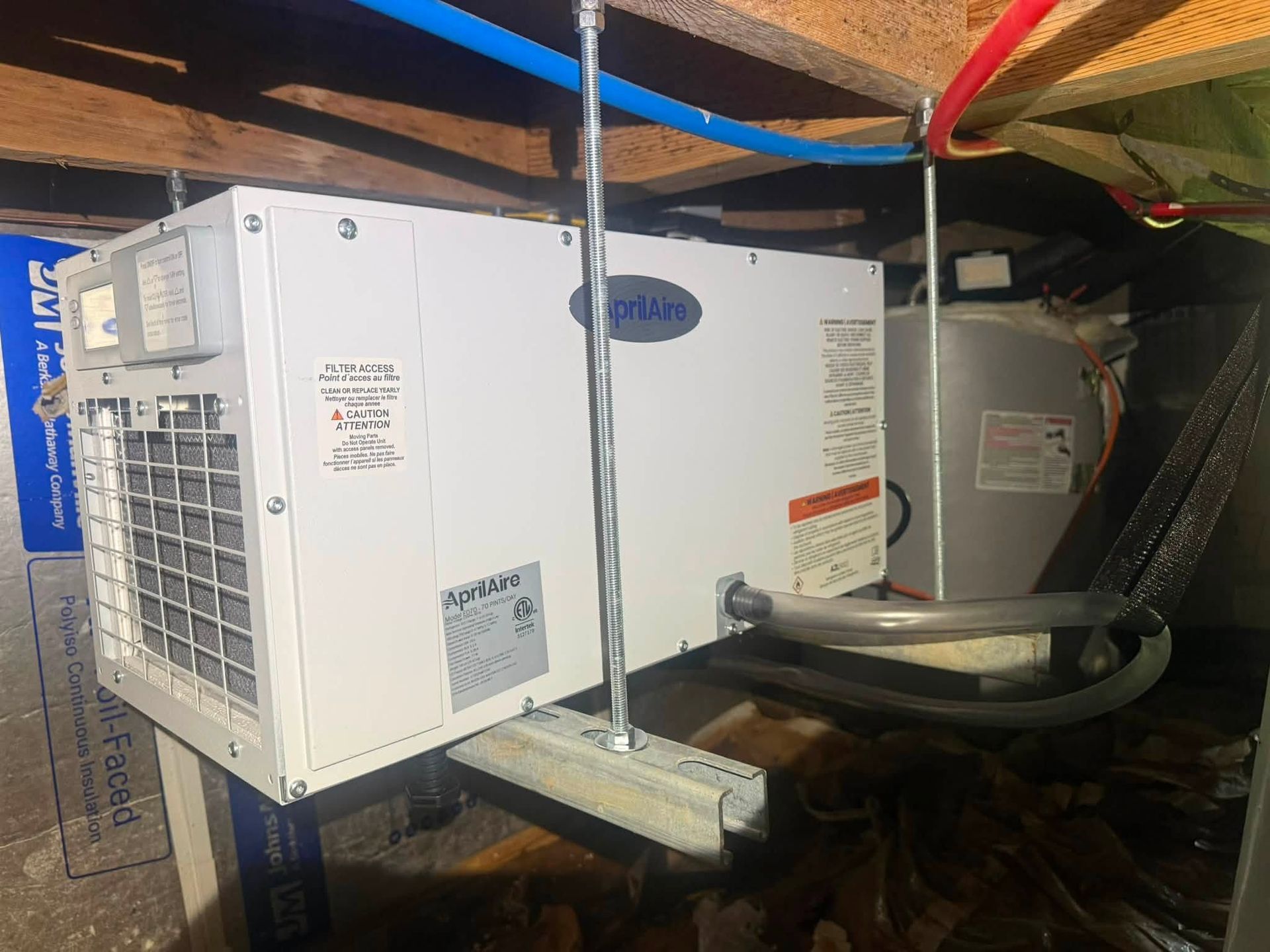 White HVAC unit mounted in a cramped attic space with exposed ducts and wiring