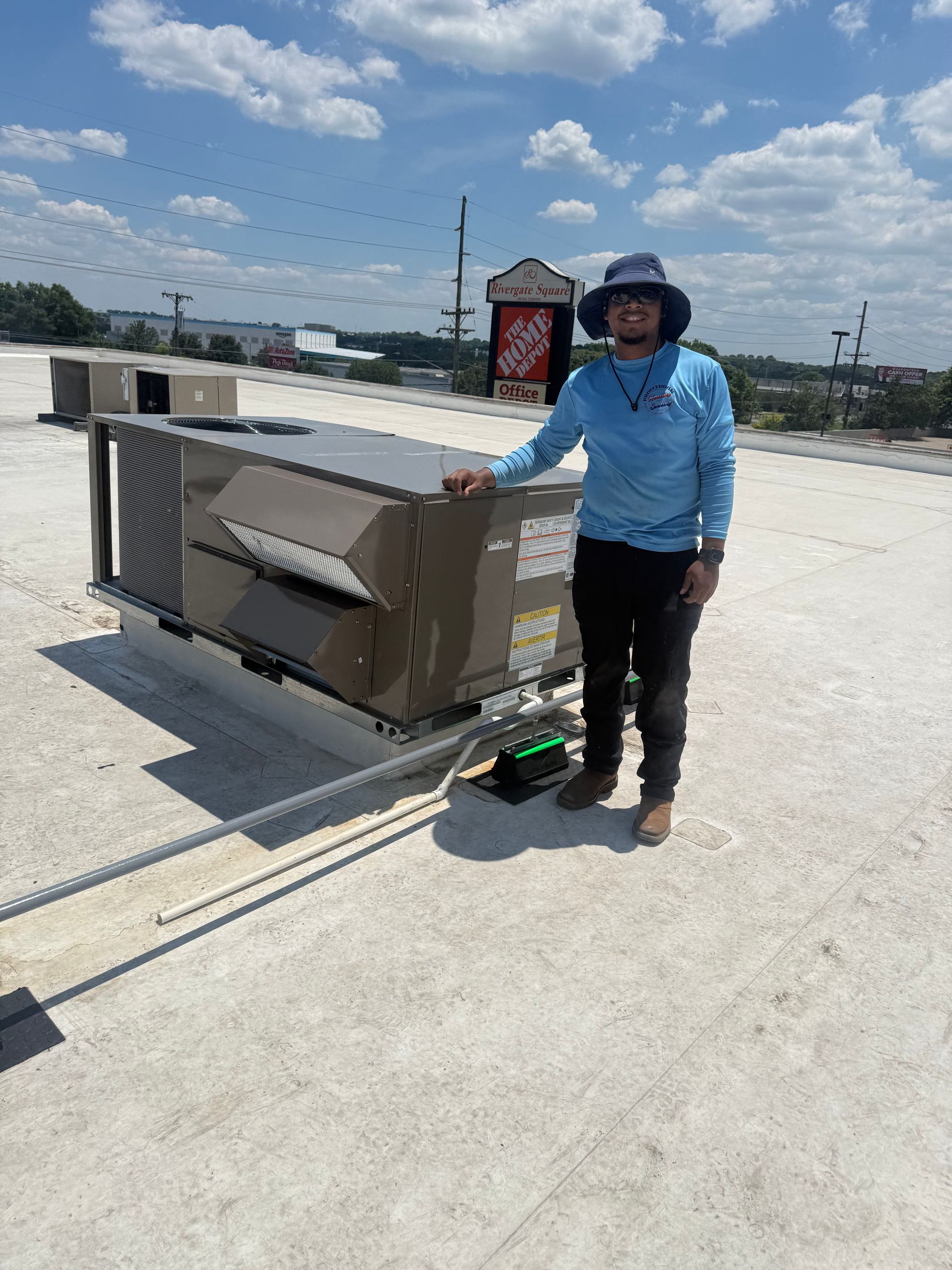 Person standing beside a large cart on a sunny rooftop, wearing a blue shirt and hat.