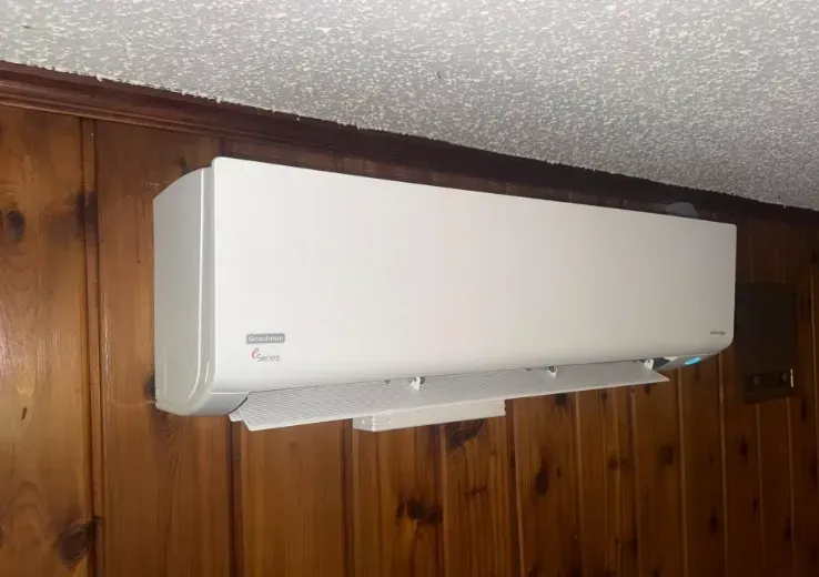 White wall-mounted air conditioner on wood-paneled wall indoors