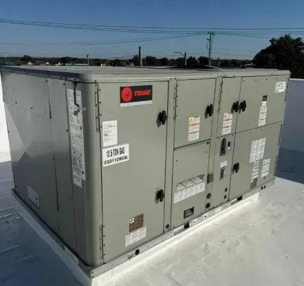 Gray Trane rooftop HVAC unit on a flat white roof under a clear sky