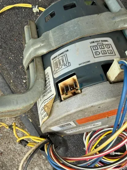 Close-up of a motor with wiring harness and yellow cables on a concrete floor
