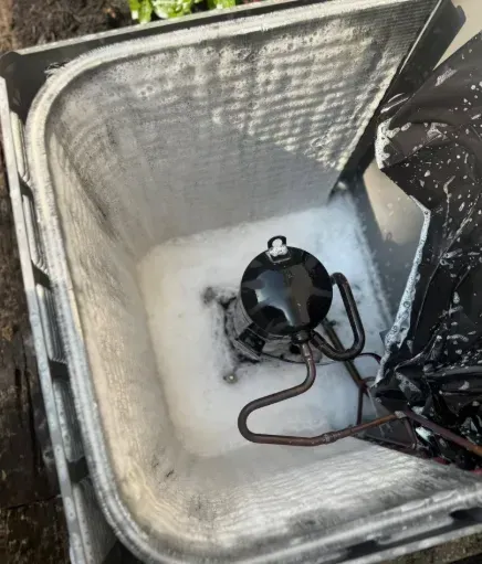 Open white cooler with a black portable stove and copper tubing inside