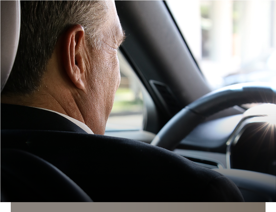 Driver seen from behind holding the steering wheel inside a car