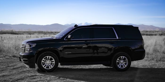 Black SUV parked on a gravel plain with mountains in the background under a clear sky
