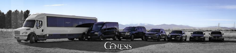 White luxury buses lined up in a desert lot with the GENESIS logo in front of mountains