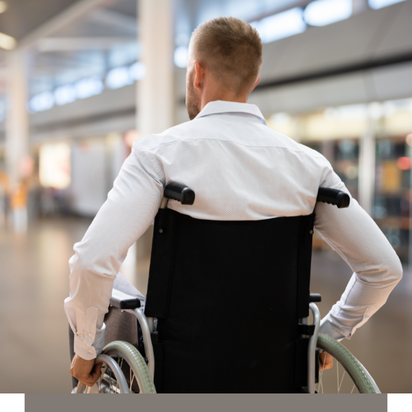 Person in a wheelchair seen from behind in a bright indoor transit terminal