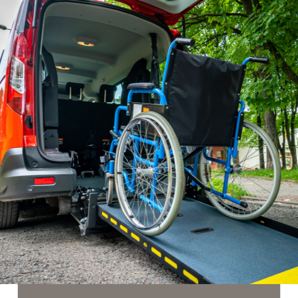 Wheelchair on a van ramp beside an orange and gray accessible vehicle outdoors