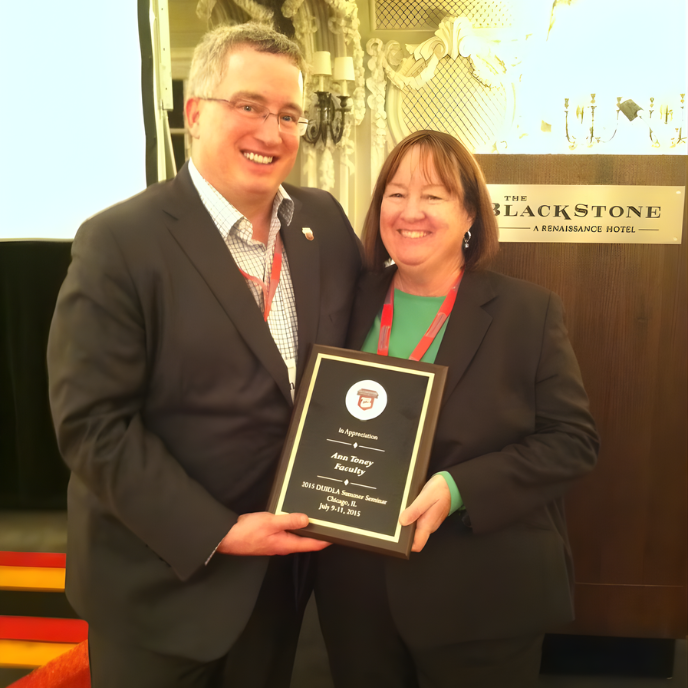 Two people in business attire holding an award plaque at a Blackstone event, smiling.