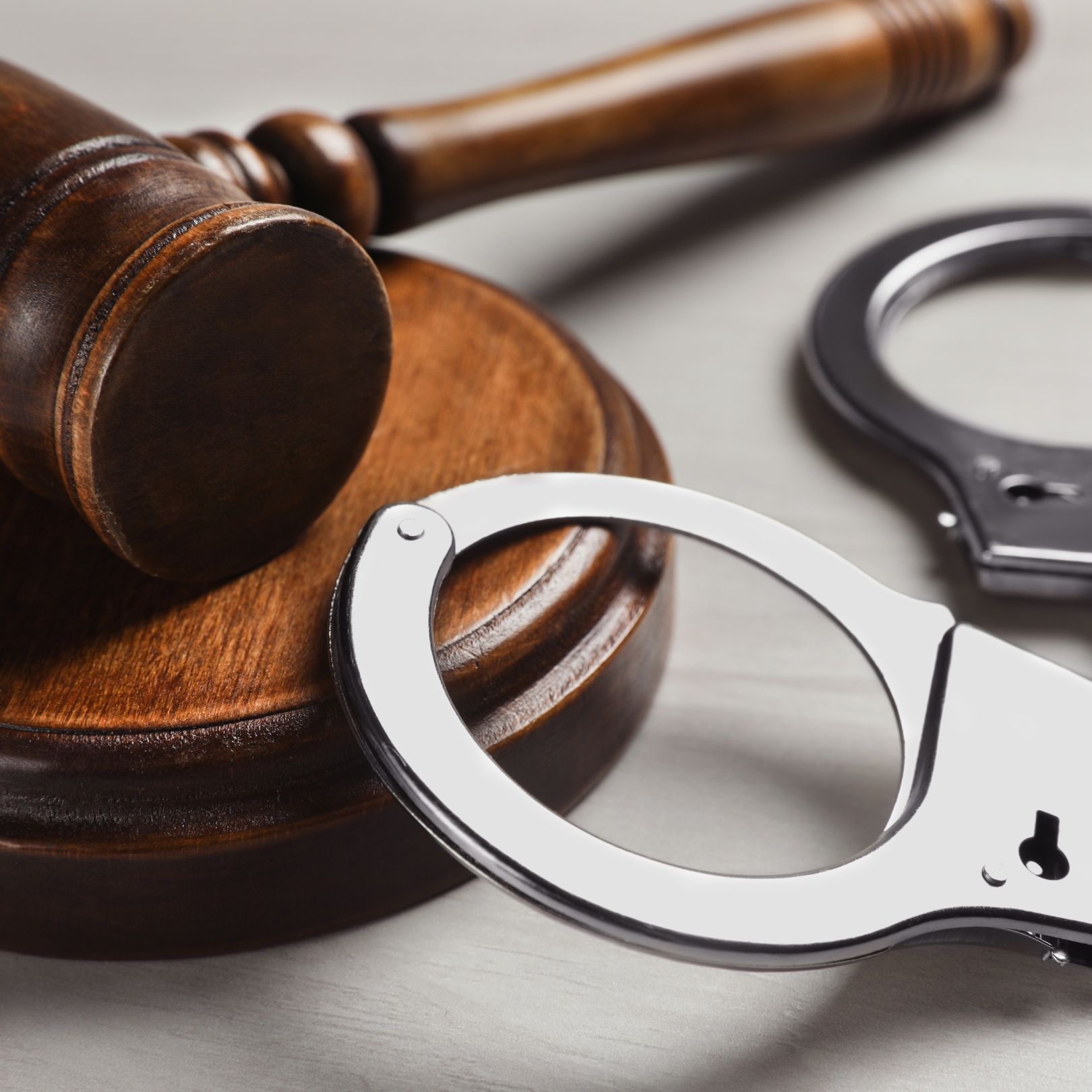 Wooden judge’s gavel beside silver handcuffs on a table