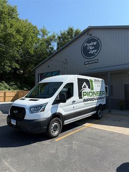 White Pioneer Innovations van parked outside a gray industrial building with a circular sign.