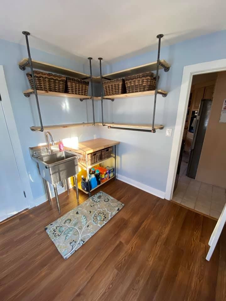 Corner pantry nook with metal shelves, woven baskets, and a small table on hardwood floor