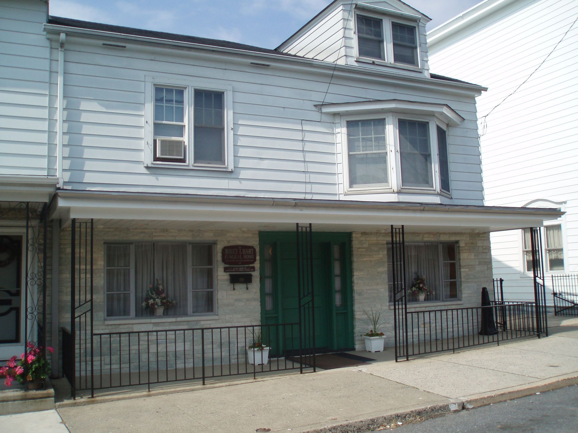 A white house with a green door and a black railing