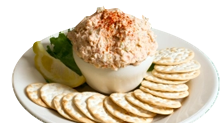 Crab dip with crackers, lemon wedge, and lettuce on a white plate.