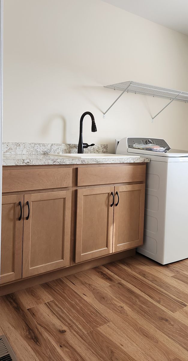 A laundry room with a sink, countertop, cabinets, washer and dryer.