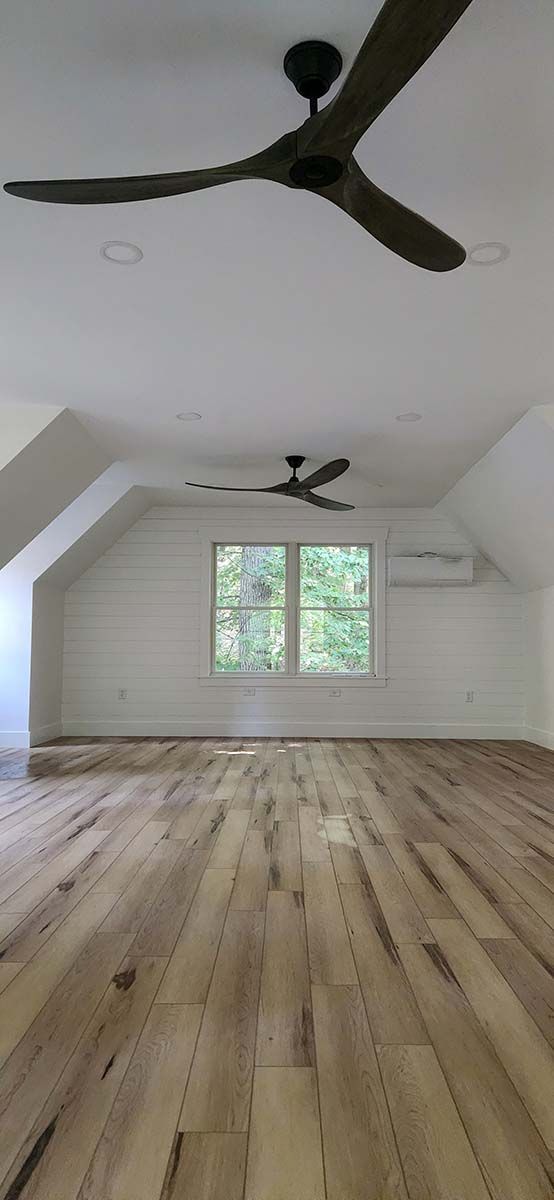 An empty room with hardwood floors and two ceiling fans.