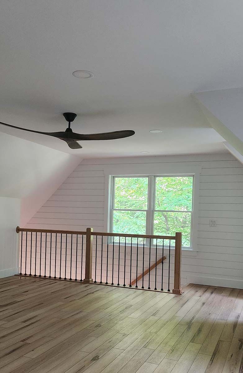 An empty room with a wooden floor and a ceiling fan.